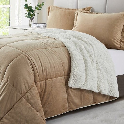 Tan plush comforter with a fluffy white throw blanket and matching pillows on a bed in a light-filled bedroom